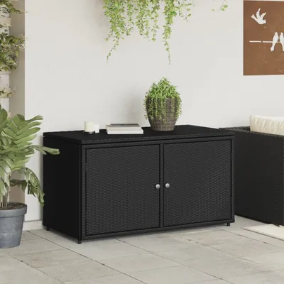 A black poly rattan garden cabinet with two doors, placed on a tiled patio next to a wall with hanging plants.