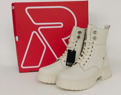 A pair of beige Rieker lace-up boots are displayed next to their red branded box.