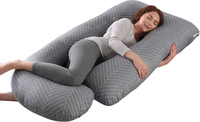 A woman is sleeping on a large J-shaped pillow.