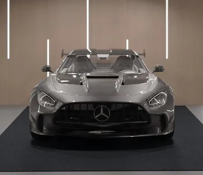 A front view of a gray sports car on a dark mat in a showroom.