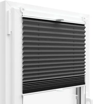 A close-up view of a dark gray pleated blind installed in a white window frame.