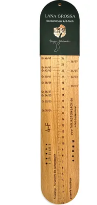 A wooden sock ruler with size markings and brand information.