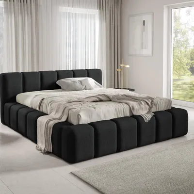 A modern black upholstered bed with pillows and a throw blanket, set in a bright, minimalist bedroom with sheer curtains and a large window.