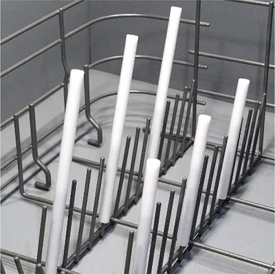 A close-up view of white cylindrical objects placed vertically in a gray metal rack, likely a dishwasher basket.