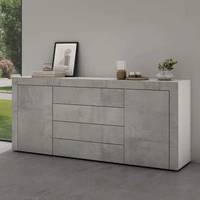 A modern sideboard with a concrete-look finish and white accents, placed in a room with a large window showing greenery outside.