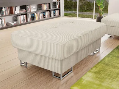 A beige corduroy ottoman with silver metal legs is placed on a wooden floor in front of a bookshelf.