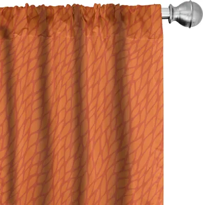 A close-up of an orange curtain with a leaf-like pattern, hanging from a curtain rod.