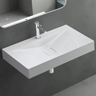 A modern white rectangular wall-mounted sink with a single faucet hole and a sleek, minimalist design, set against a dark gray wall.