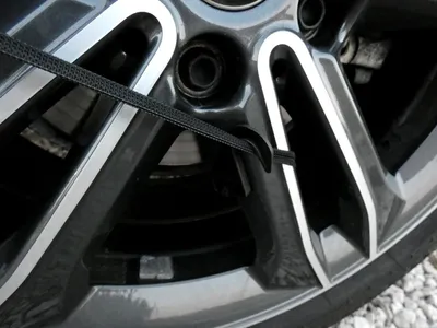 A close-up view of a car wheel with a black strap attached.