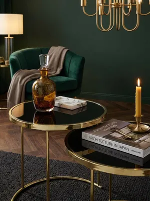 Kleiner Wohnzimmertisch aus Glas und Metall stilvoll dekoriert mit einer Teetasse und Notizbuch unter einer messingfarbenen Stehlampe_#sku_SAFWL5.769#