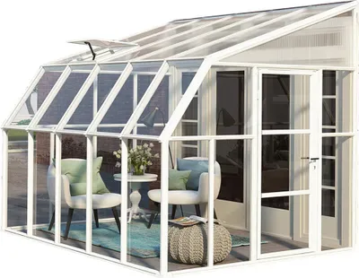 A white greenhouse with furniture inside, set up as a sunroom.