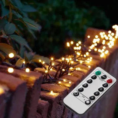 Fairy lights are wrapped around a brick wall, with a remote control in the foreground.