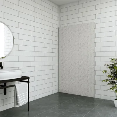 A modern bathroom with white subway tiles on the walls and a large, textured gray panel on the right wall. A white sink is mounted on a dark metal stand with a gray towel hanging from it. The floor is dark gray.