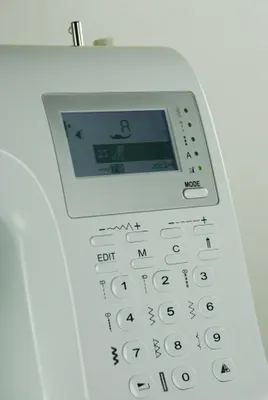 A close-up view of the control panel and screen of a white sewing machine.