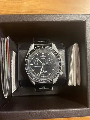 A watch is displayed in its box with some accompanying documents.