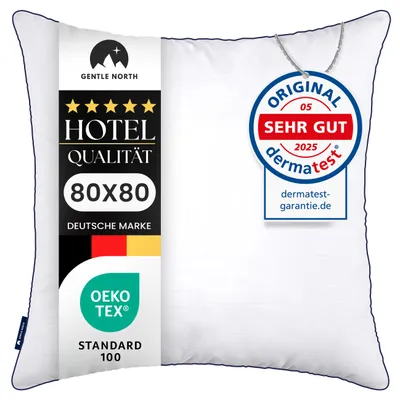 A white pillow with a label on the left side and a circular tag attached to the top right corner.