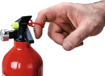A close-up shot of a hand using a red fire extinguisher.