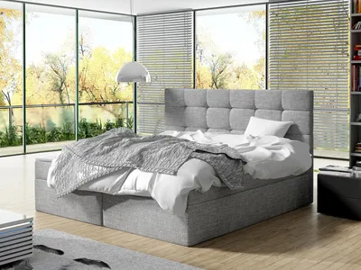 A bedroom with a large window overlooking trees in autumn.