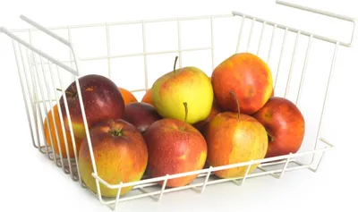 A white wire basket filled with apples and oranges, placed on a white surface.
