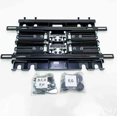 A black full motion slim TV wall mount with two bags of hardware in front of it.