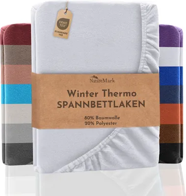 A white fleece fitted sheet is displayed prominently, with a band of text across the front. Several other fitted sheets in various colors are stacked behind and to the sides.