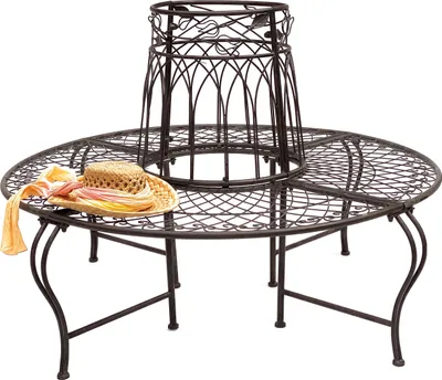 A round metal garden bench with a decorative lattice pattern, designed to surround a tree trunk. A straw hat and scarf are placed on the bench.