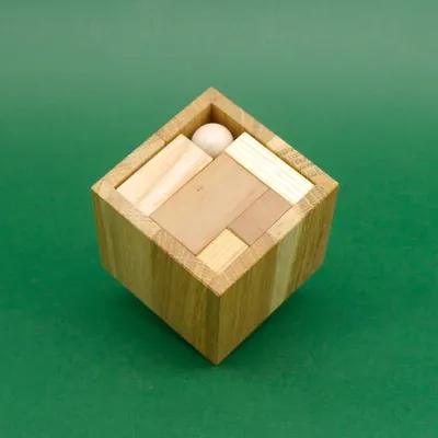 Quadratische Holzbox von oben, alle Teile des Teapico-Puzzles passgenau verstaut.