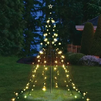 A lighted Christmas tree decoration in a yard at night.