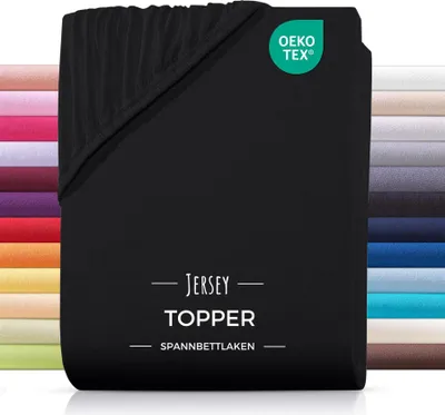 A black jersey topper fitted sheet is shown folded, with a stack of other colored fitted sheets visible behind it.