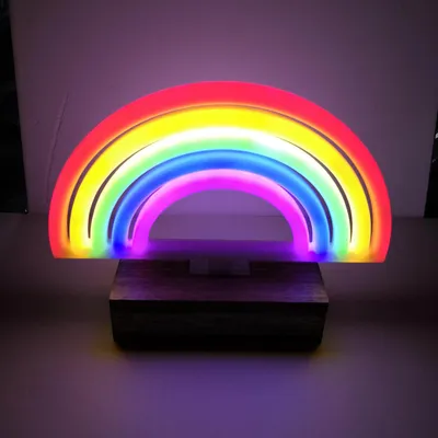 A neon LED rainbow light is displayed on a wooden base against a light gray and white background.