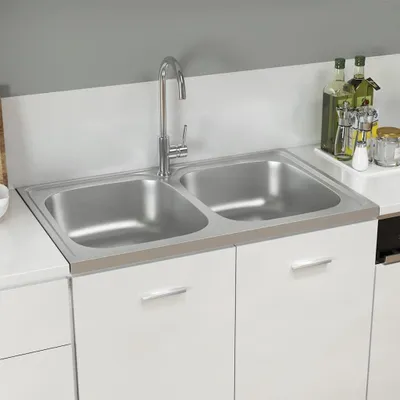 A double kitchen sink with a faucet and some bottles on the counter.