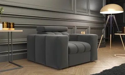 A modern living room with a gray armchair, a side table with decorative items, and a floor lamp.