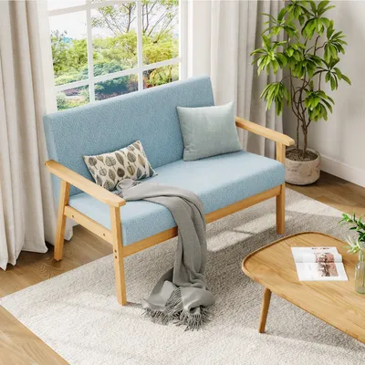 A light blue sofa with wooden legs is placed in a well-lit room with a large window and a potted plant.
