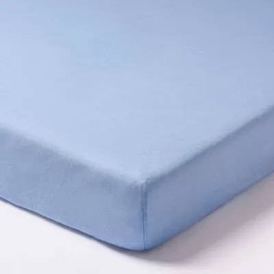 A close-up, angled view of a light blue fitted sheet, showing the corner seam.