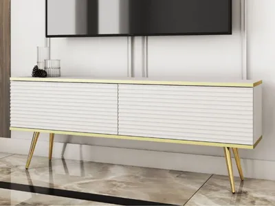 A white and gold TV stand with a fluted front is shown in a room with a television above it.
