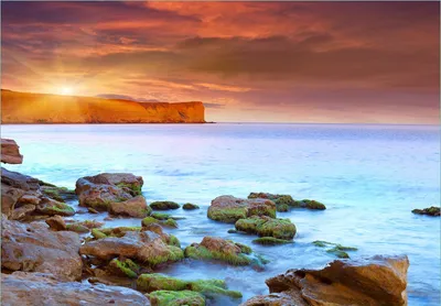 Produktbild von Wallario Fototapete Vliestapete, seidenmatte Oberfläche, einfache Verarbeitung, Größe 350 x 245 cm, Motiv Sonnenaufgang am Meer mit Landzunge und Felsen im Wasser