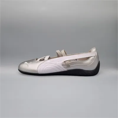 A side view of a silver and white Puma Speedcat Ballet shoe against a plain gray background.