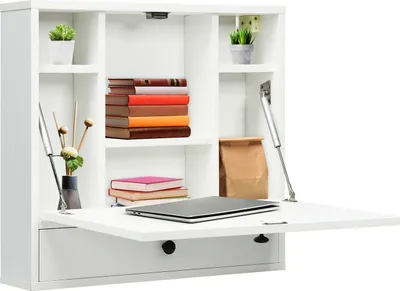 A white wall-mounted desk with shelves and a fold-down table is shown against a white background. The desk contains books, plants, and a laptop.