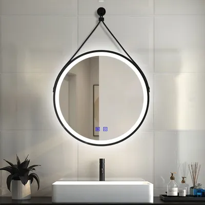 A round LED mirror with a black frame hangs above a modern sink in a bathroom.