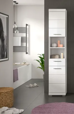 A modern bathroom with a tall white cabinet, a bathtub, and a plant.