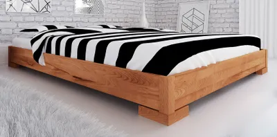 A wooden bed with black and white striped bedding in a room with a brick wall.