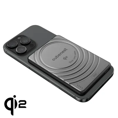 A dark gray smartphone with a magnetic wireless charger attached to its back.