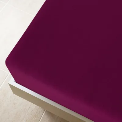 A close-up view of a purple fitted sheet on a bed frame.