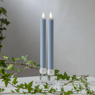Two blue LED candles in clear glass holders, with ivy branches in the foreground.