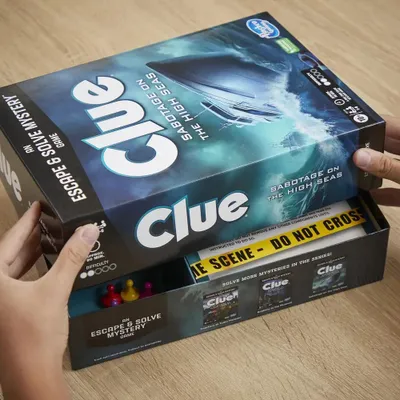 A person's hands are opening a board game box.