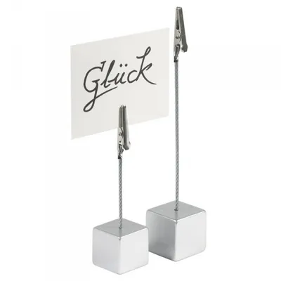 Two silver cube-shaped card holders with clips, one holding a white card with the word "Glück" written in black script.