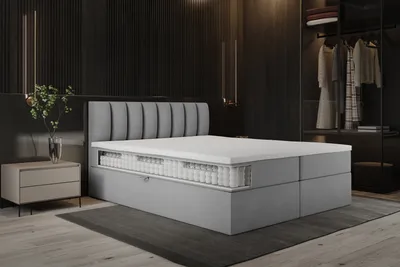 A modern bedroom with a boxspring bed, nightstand, and open closet.
