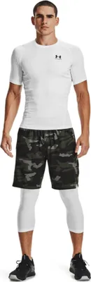 A man wearing athletic wear, including a white t-shirt and camouflage shorts, stands facing the camera.