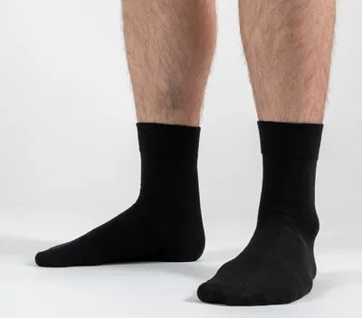 A close-up shot of a person's legs wearing black socks against a white background.