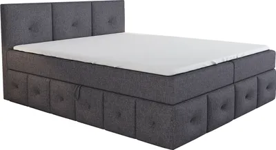 A grey boxspring bed with a mattress and topper, shown from a side angle against a white background.